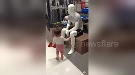 Adorable moment polite toddler greets mannequins inside shopping mall