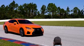 Cameras film a car speeding around a racetrack.