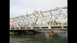 Kids in Indonesia cool off by jumping off bridge into a river