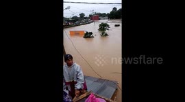 Locals stay dry by climbing onto roofs as flood levels rise in South Sulawesi, Indonesia