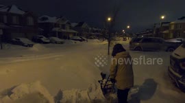 man snowblowing driveway early in the morning after snowstorm