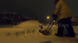 Man snowblowing driveway after snowstorm