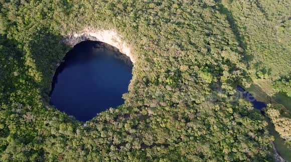 Aerial view of the Candelaria cenote, with people having fun diving from a rock