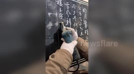 Skilful man shows off calligraphy on stone slab using a power grinder