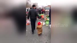 Smart dad uses strawberry to encourage son to follow him through market