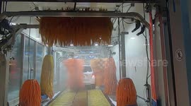 POV shot going through automatic car wash in the winter to wash off the road salt and slush to prevent corrosion and rust