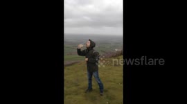 Attempting to have a drink during Storm Gareth on The Wrekin, Shropshire.