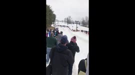 Competitors in cardbosrd sled race dressed as Batmen win for the 2nd consecutive year, blasting through the rentaining fence.