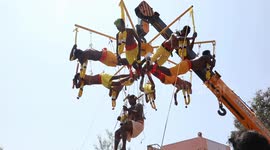 Hindu devotees display their devotion by piercing skin with metal hooks and hanging from crane