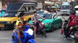 Young boy left in dad's sports car directs passing traffic while waiting