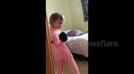 Diva-like toddler caught posing in mirror with Mum's ear muffs