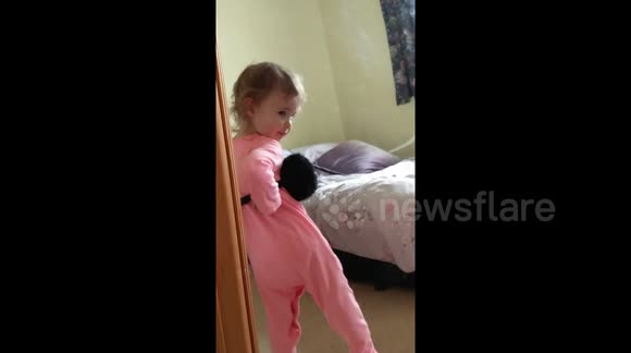Diva-like toddler caught posing in mirror with Mum's ear muffs