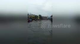 Hundreds of women wade through waist high water after road floods in Indonesia