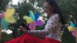 Thai lady relaxes on bench with Tablet and wind chimes.