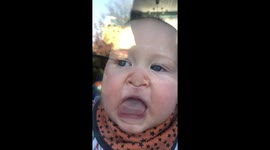 Baby pulling funny faces against a window