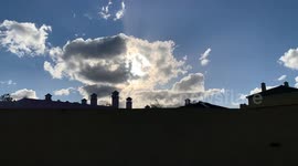 time lapse clouds behind sun with Silhouette of rooftops