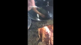 The man uses hand to process tea leaves on a hot fire pan