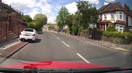 Idiot playing chicken on one wheel with an oncoming ambulance and traffic approaching traffic lights