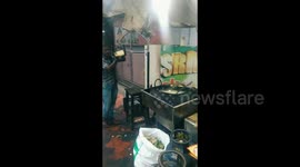 Chef in India lands potato slices into frying pan while standing a few feet away