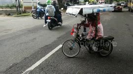 Man with no legs gets around Indonesian city by hand-pedalling tricycle