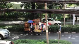 How can he see? Man on bike full of brooms rides through busy Bangkok street