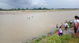 Children walk across a flooding river to attend school
