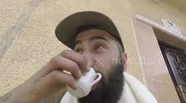 Kurdish fighter calmly sips coffee while suspected IS fighters shoot at him
