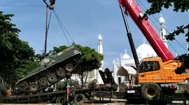 crane lifts steel tanks to be moved into a photo spot on the Padang coast