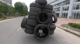 An overloaded motorbike carrying 19 big car tires when driving fast in Vietnam