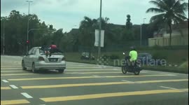 Reckless driver in Malaysia is caught jumping red light with two children clinging to roof