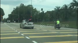 Reckless driver in Malaysia is caught jumping red light with two children clinging to roof