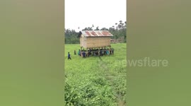 Community effort! Filipino villagers help neighbour carry house to new location