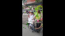 Filipino newlyweds ride away from ceremony sitting together on husband's old pushbike