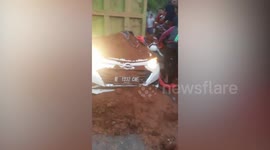 Rescuers battle to reach family trapped in car crushed by overturned lorry in Indonesia