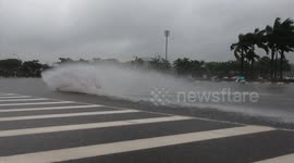 Cars create beautiful water waves when driving through flooded road