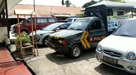 a cat relaxes under a police car when the temperature in Padang is very hot