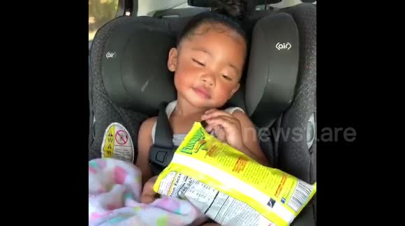 Precious toddler tries her best to stay awake while eating snacks