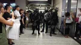 Riot Police form a defensive line outside Kwun Tong MTR Station as local residents look on confused and nervously