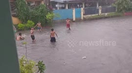 Filipino children make the most of the bad weather by playing in flooded street