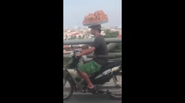 Man has breadbasket strapped to his head while motorbiking in Vietnam