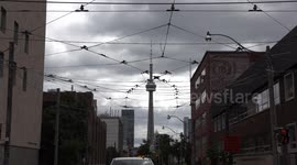 Toronto CN tower with ominous dark clouds in the background and trolley wires in the foreground