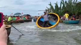 Vietnamese man rapidly spins rowing boat in circular motion while on river
