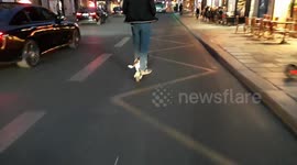 Man rides on electric scooter with dog between his legs on busy Paris roads