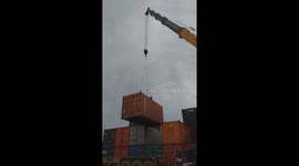 The man risked his life working the rope of the crane and stand on the container