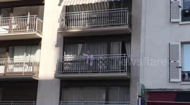 Elderly woman blows kisses to climate strikers marching below her balcony