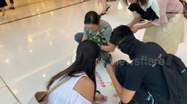 Three ladies join a younger frontline protester in putting stickers on the floor of a mall