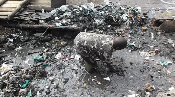 Man in Kenya sifts through knee-deep waste to clear out plastic