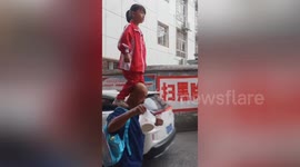 Girl balances on grandfather's shoulders while being taken to school