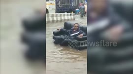 Ingenious man uses inflatable couch to sail through inundated road in northern India