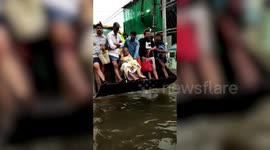 Officials use excavator while moving people to safer places in flood-hit northern India